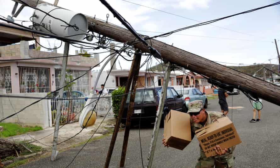 A member of the Puerto Rican National Guard dodges downed power cables as he hands out food and water to a neighborhood in Ceiba, Puerto Rico Wednesday.