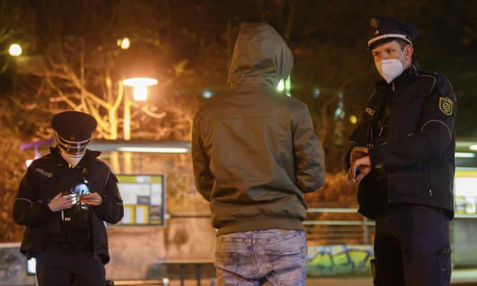 Police officers talk to a man in the Gorbitz district in Dresden, Germany.