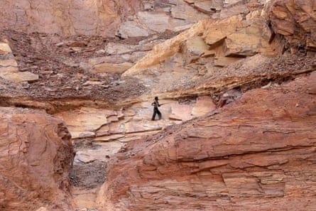 A small figure works on the stone surrounded by huge walls of rock.