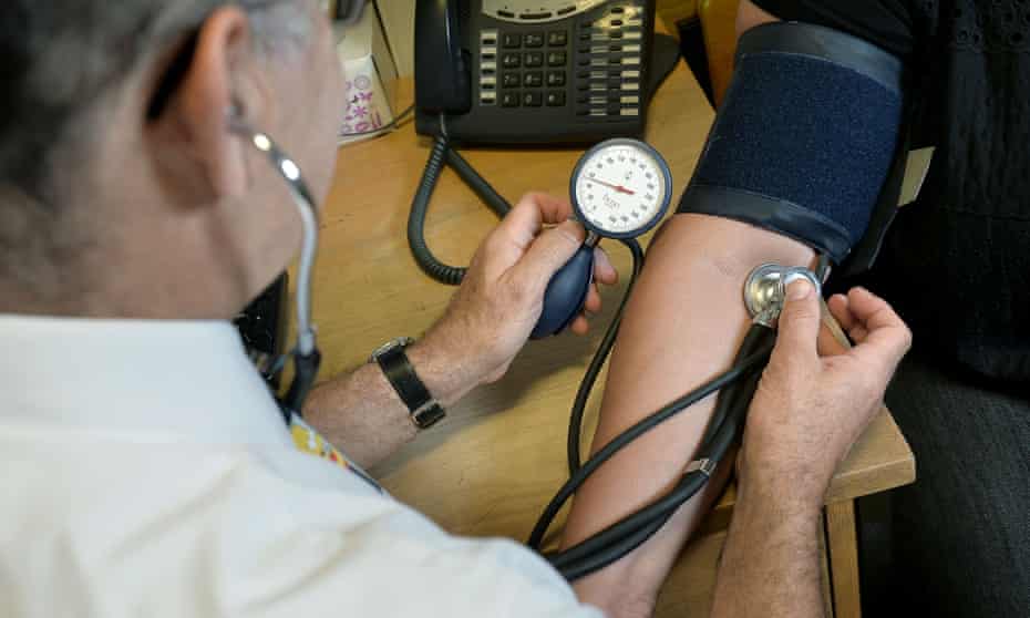 A GP checks a patient’s blood pressure. 