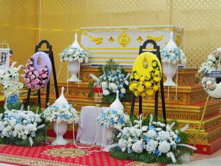 The wreaths of Thailand’s king and queen stand beside the casket of Naphat Chaimar.