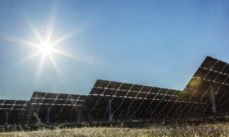 Solar panels at a solar farm with the sun shining overhead