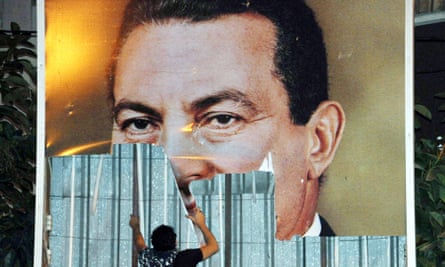 A protesters tearing down a poster of President Hosni Mubarak during a protest in Alexandria on 25 January 2011.