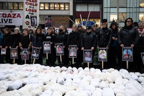 Protesters in New York stand in front of small effigies made to represent children. At the back, people hold pictures of children alleged to have been killed in the war in Gaza