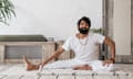 Yoga teacher Ravi Dixit all in white with one leg stretched out to his side