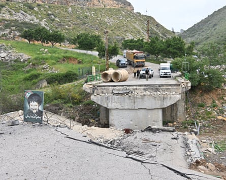 People stand at the far side of a destroyed bridge
