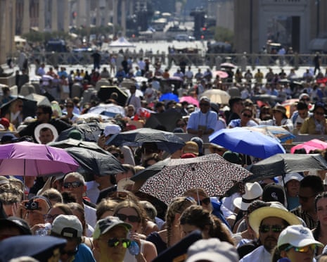 Faithful take shelter from the sun as they wait for the arrival of Pope Leo XIV for his general audience in St. Peter's Square at the Vatican.