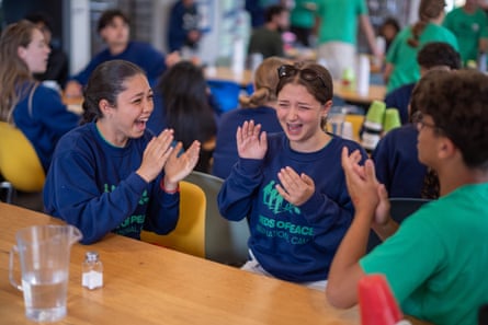 Group sat at a table in navy and green Seeds of Peace T-shirts laughing together