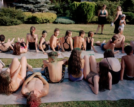 Children sit on an impromptu water slide on the grass in their bathing costumes