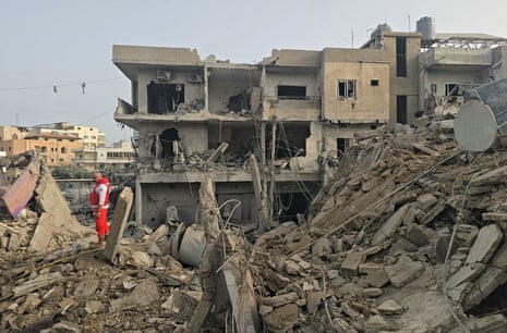 A rescue worker stands atop rubble of a building destroyed in an airstrike.