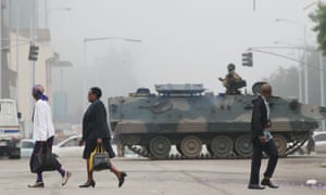 People walk past an armoured vehicle in Harare,
