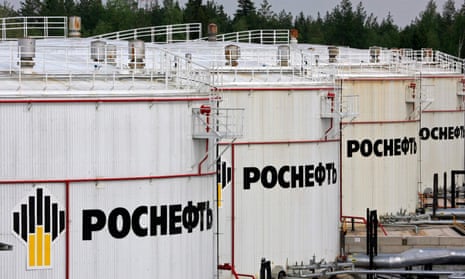 A row of very large white oil staorage tanks with the Rosneft name and logo, written in Cyrillic