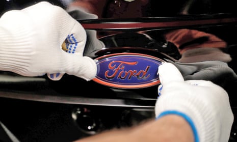 A worker attaches the Ford logo to a Fiesta car at the plant in Cologne, Germany