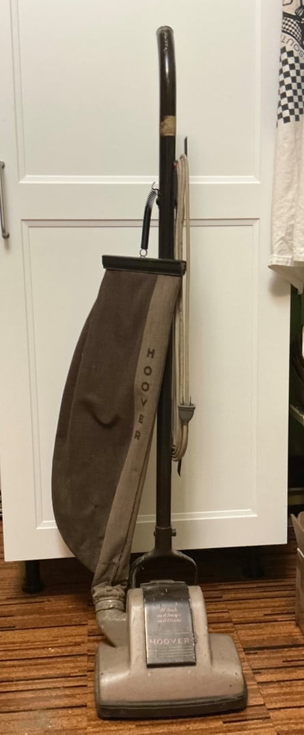 An upright vacuum cleaner with a brown material dust bag attached by a spring