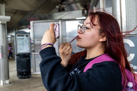 A woman with red hair puts on lipstick