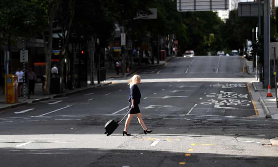 A woman crosses an empty George Street during the morning peak hour in central Brisbane.