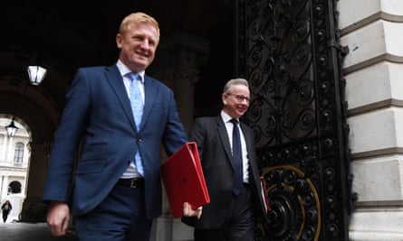 Oliver Dowden and Michael Gove walk through an archway carrying ring-binder files
