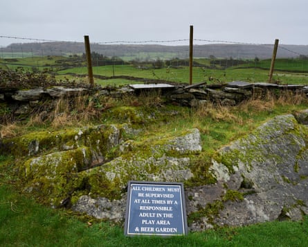 An abandoned garden, with a sign left next to a wall saying ‘All children must be supervised at all times by a responsible adult in the play area & beer garden;