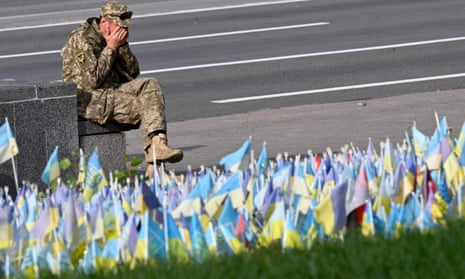 A Ukrainian serviceman sits in front of Ukrainian flags symbolising fallen Ukrainian soldiers, at a makeshift memorial site at the Independence Square in Kyiv.