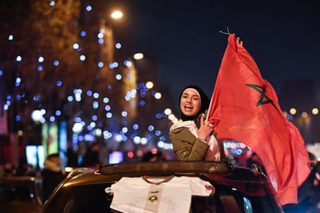 A Morocco supporter waves a national flag to celebrate the win on the Champs Elysees in Paris.