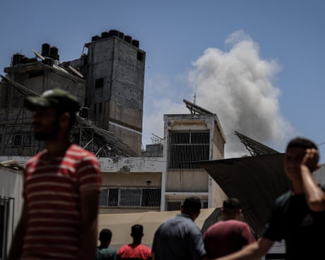 People in the foreground look at smoke from a fire rising above buildings