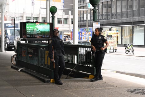 Two police officers at the top of a sidewalk-level subway entrance.