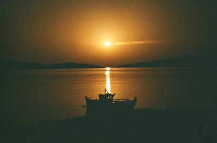 A fishing boat silhouetted by the sun