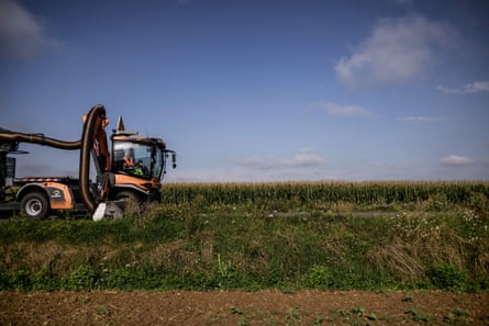 An agricultural vehicle being driven through a field of plants on a sunny day