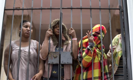 People stand behind a gate at the entrance of an abandoned residential apartment building in Flamengo neighborhood of Rio de Janeiro, Brazil. Squatters invaded the residence and demanded city officials put them into social housing.