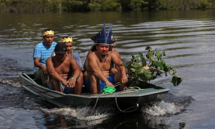 Indigenous Amazonian men wearing headdresses in a boat on a river