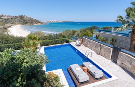 Overhead shot of an outdoor pool with a platform with wooden beds on it and a view of a bay