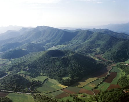 Volcanic cone set amid green woods and fields near the Pyrenees in north-east Spain