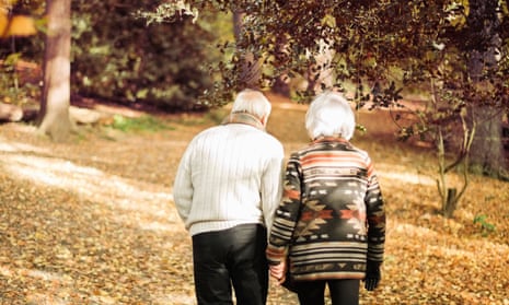Older couple walking together in park.