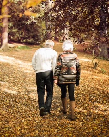 Older couple walking together in park.