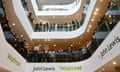 Staff at a John Lewis and Waitrose store look out over a glass mezzanine with the store signs visible