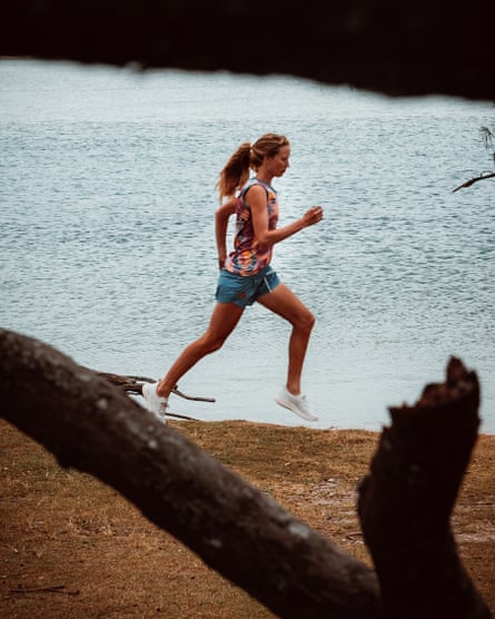 Australian ultra-marathon runner Erchana Murray-Bartlett, running along the sand on a beach. She is wearing blue shorts and a bright multicoloured top
