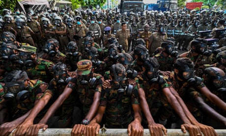 Soldiers behind barriers hold back protesters