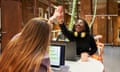 Two work colleagues giving each other high-five to express success while sitting at their workstations<br>Portrait of two multiracial work colleagues giving each other high-five to express success while sitting at their workstations.