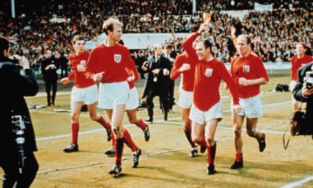 Jack Charlton regarde en direction de Ray Wilson, qui tient le trophée, et de Bobby Charlton alors que l'Angleterre célèbre sa victoire à la Coupe du monde.