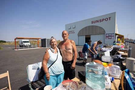 George stands with his arm around Colleen’s shoulder at a stall in a large car park