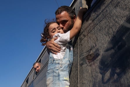 A man kisses his daughter through the window of the bus