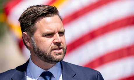 a man in a suit and tie speaks in front of an American flag
