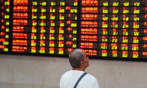 An investor watches an electronic ticker board at a stock market in Nanjing, China