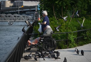 Old lady in a wheelchair and carer sit by the river enjoying the view.