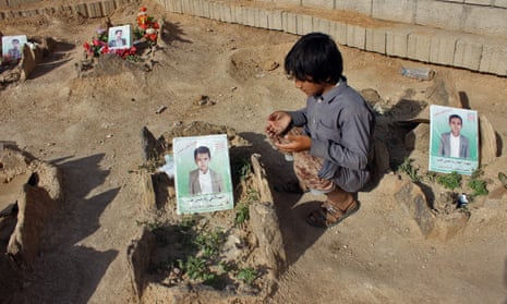 A Yemeni boy recites a prayer by the graves of pupils killed