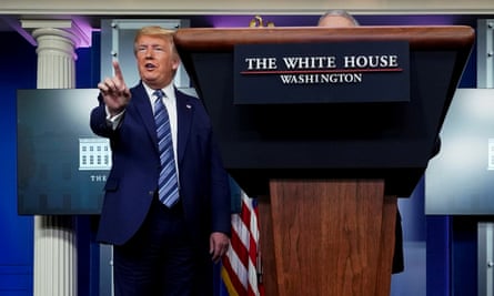Donald Trump stands next to a podium in the White House press room with a finger up, pointing toward the audience.