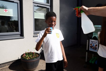 A pupil is sprayed with a fine mist as they drink water at the Harris Academy Primary Maxyflower school, in Grays, UK.