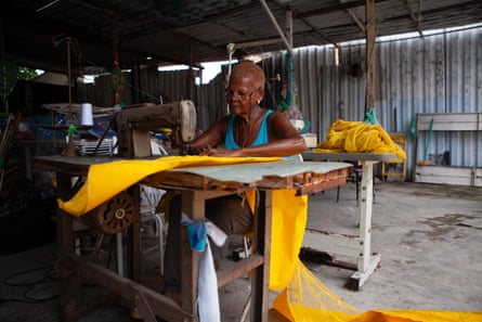 A black women sews yellow fabric at a sewing machine