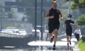 Joggers on a sidewalk during a heatwave in Tokyo in August 2020.