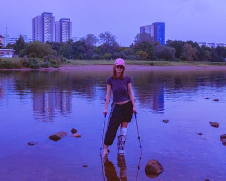 The musician Betty Hammerschlag on crutches, standing in a river